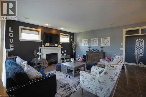 Living area featuring a white mantel fireplace, recessed lighting, two windows with blinds, wood-finish flooring, and a decorative doorway with an arched transom - 365 Poldon Drive, Norwich, ON 