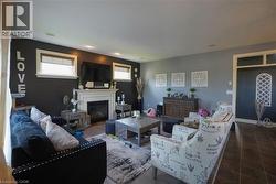 Living area featuring a white mantel fireplace, recessed lighting, two windows with blinds, wood-finish flooring, and a decorative doorway with an arched transom - 