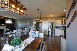 Open-concept living space featuring a central dining area with a wood-finish table and an overhead linear chandelier - 