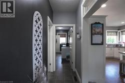Hallway featuring dark gray walls, white trim, and tile flooring, opening to a kitchen with light cabinetry and wood-finish flooring - 