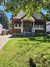 Brick facade residence featuring white siding, a covered entryway, front garden beds, and a paved driveway - 153 Arnold Street, Kitchener, ON 