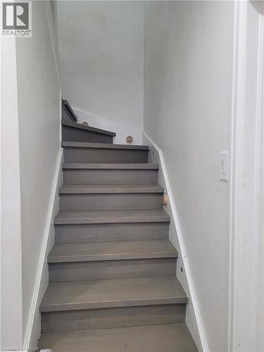 Staircase featuring wood-finish treads and risers, white painted stringers, and light gray wall paint - 153 Arnold Street, Kitchener, ON 