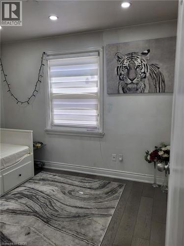 Room featuring dark wood-finish flooring, recessed ceiling lighting, and a window with horizontal blinds - 153 Arnold Street, Kitchener, ON 
