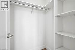 Walk-in closet featuring white built-in shelving, a hanging rod, and baseboard trim - 