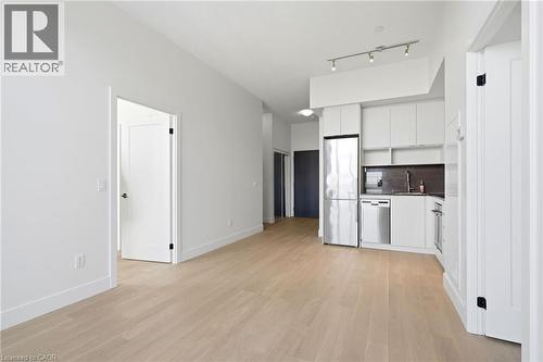 Open-concept living area featuring light wood-finish flooring, white walls, and a contemporary kitchen - 7 Mabelle Avenue Unit# Ph07, Toronto, ON 