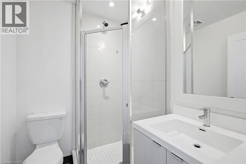 Bathroom featuring a white vanity with integrated sink, chrome faucet, wall-mounted mirror, and glass-enclosed shower with tile surround - 7 Mabelle Avenue Unit# Ph07, Toronto, ON 