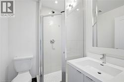 Bathroom featuring a white vanity with integrated sink, chrome faucet, wall-mounted mirror, and glass-enclosed shower with tile surround - 