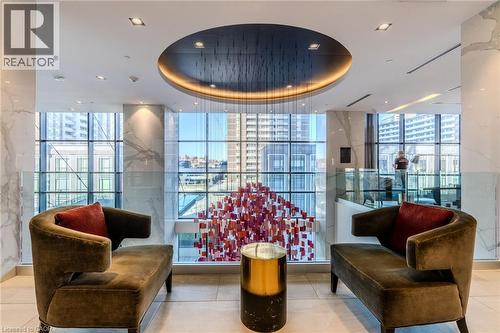 Lounge area featuring a circular recessed ceiling with accent lighting, full-height windows, a modern art installation, two contemporary chaises, and a metallic accent table - 7 Mabelle Avenue Unit# Ph07, Toronto, ON 