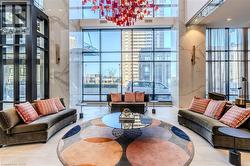 Grand lobby space featuring a striking red and orange geometric chandelier, floor-to-ceiling windows, and polished marble wall accents - 