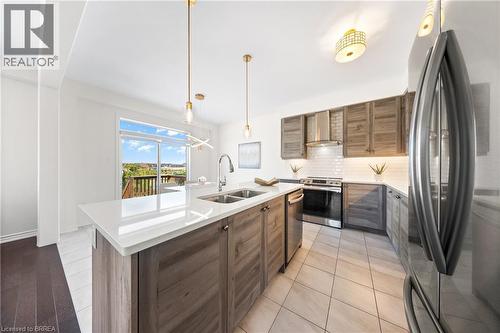 Kitchen with stainless steel appliances, decorative backsplash, modern cabinets, decorative light fixtures, and light tile patterned flooring - 1 Bee Crescent, Brantford, ON 