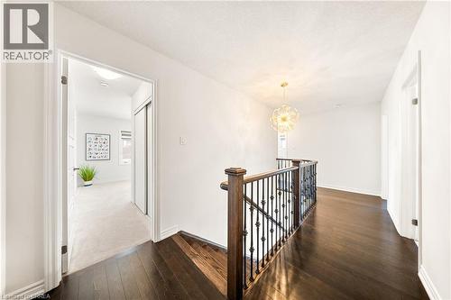 Hallway featuring an upstairs landing, dark wood finished floors, and a chandelier - 1 Bee Crescent, Brantford, ON 