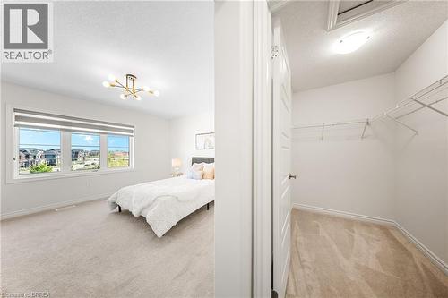 Bedroom featuring light carpet, a textured ceiling, and a chandelier - 1 Bee Crescent, Brantford, ON 