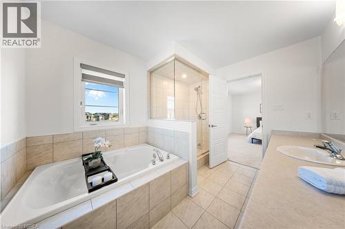 Full bathroom with connected bathroom, a shower stall, a garden tub, light tile patterned flooring, and vanity - 1 Bee Crescent, Brantford, ON 