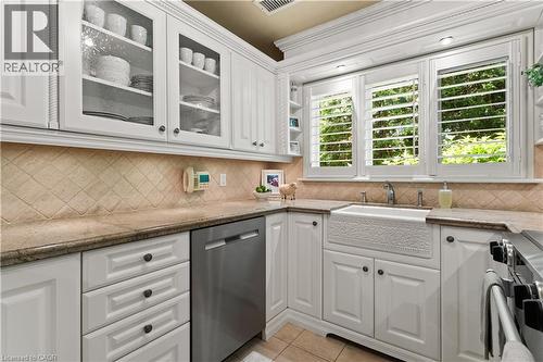 Kohler sink, tapsets, soap dispenser, hand spray. ""Seedy"" glass on cabinetry. Plantation shutters. Maytag dishwasher - 3040 First Street, Burlington, ON - Indoor Photo Showing Kitchen