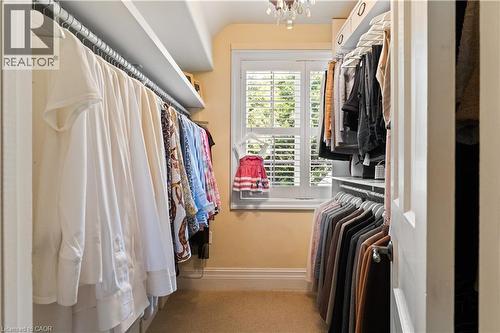 Primary bedroom closet. California shutters. Chandelier. Generous amount of shelving. - 3040 First Street, Burlington, ON - Indoor With Storage