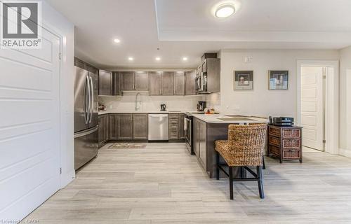 Kitchen featuring wood-finish flooring, stainless steel appliances, dark wood cabinetry, light countertops, and recessed lighting - 5 Wake Robin Drive Unit# 107, Kitchener, ON 