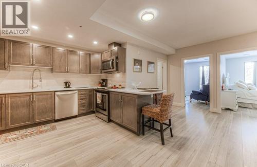 Kitchen featuring wood-finish cabinetry, light-toned countertops, and a subway tile backsplash - 5 Wake Robin Drive Unit# 107, Kitchener, ON 