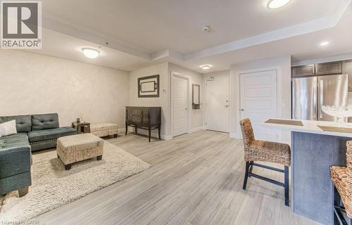Open-concept living area featuring wood-finish flooring, recessed lighting, and a kitchen island with a light-toned countertop - 5 Wake Robin Drive Unit# 107, Kitchener, ON 