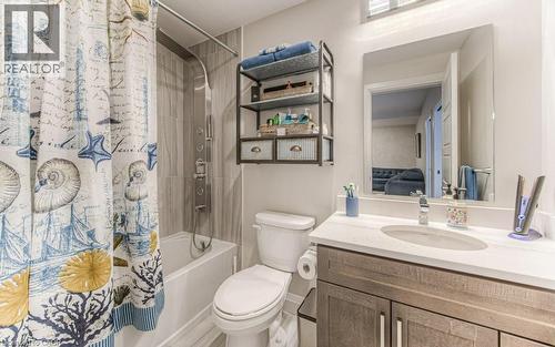 Bathroom featuring a white bathtub, a chrome multi-function shower panel, and light-toned tile surround - 5 Wake Robin Drive Unit# 107, Kitchener, ON 