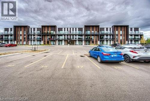 Contemporary apartment building featuring a multi-story facade with balconies, dark vertical accents, and light-colored siding - 5 Wake Robin Drive Unit# 107, Kitchener, ON 