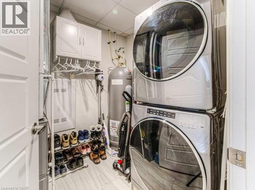 Dedicated laundry area featuring a stacked washer and dryer, white wall cabinetry, and wood-finish flooring - 5 Wake Robin Drive Unit# 107, Kitchener, ON 