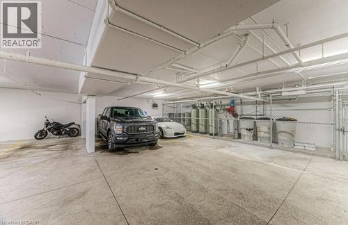 Spacious concrete parking garage with overhead piping and fluorescent lighting - 5 Wake Robin Drive Unit# 107, Kitchener, ON 