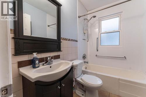 Full bathroom with toilet, tasteful backsplash, tile walls, bathtub / shower combination, and vanity - 501 Upper Wellington Street, Hamilton, ON 