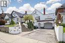 White stucco exterior featuring an integrated garage, arched entryway, and decorative facade elements - 287 Courtland Avenue E, Kitchener, ON 
