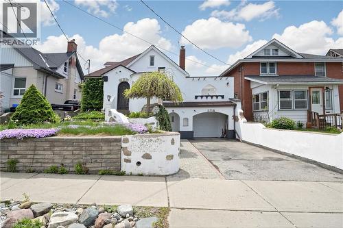 White stucco exterior with an arched entryway, integrated single-car garage, and a sloped driveway - 287 Courtland Avenue E, Kitchener, ON 