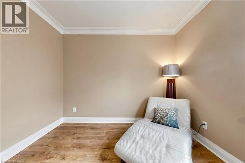 Room featuring wood-finish flooring, neutral wall tones, white baseboards, and crown molding - 287 Courtland Avenue E, Kitchener, ON 
