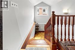 Staircase featuring wood-finish treads and risers, a wood-finish handrail, and white walls - 