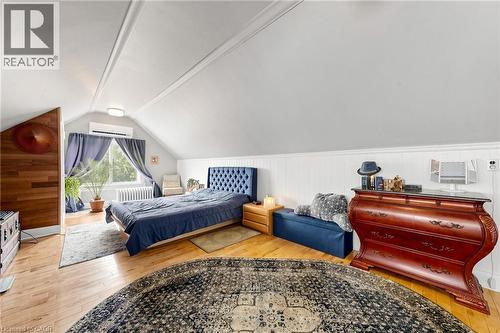 Sloped ceiling room featuring wood-finish flooring, a window with natural light, a built-in AC unit, and wainscoting - 287 Courtland Avenue E, Kitchener, ON 