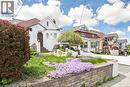 Charming stucco exterior with arched entry, terraced landscaping, stone retaining wall, and mature plantings - 287 Courtland Avenue E, Kitchener, ON 