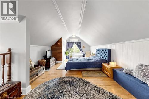 Vaulted ceiling room with wood-finish flooring, white paneled accent wall, and a window with blue drapes - 287 Courtland Avenue E, Kitchener, ON 