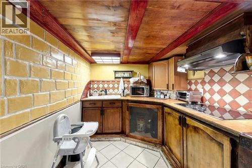 Kitchen featuring exposed wood beam ceiling, wood-finish cabinetry, tile flooring, built-in cooktop, and range hood - 287 Courtland Avenue E, Kitchener, ON 