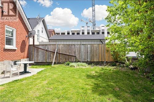Expansive backyard featuring a green lawn, concrete patio, and mature trees - 287 Courtland Avenue E, Kitchener, ON 