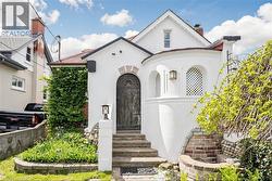 White stucco exterior with an arched wooden entry door and an arched window featuring a decorative lattice - 