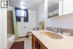 Bathroom featuring a vanity with a light-toned countertop and integrated sink, a chrome faucet, and a medicine cabinet with mirrored doors - 