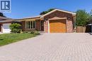 Brick exterior featuring a wood-finish garage door, paver driveway, front lawn, and mature landscaping - 12 Spartan Drive, Brantford, ON  - Outdoor 