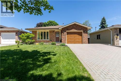 Brick exterior with a peaked roofline, featuring a single-car garage with a wood-finish door - 12 Spartan Drive, Brantford, ON - Outdoor