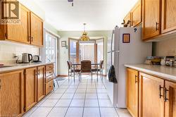 Kitchen featuring ample wood-finish cabinetry, white tile flooring, and light-toned countertops - 