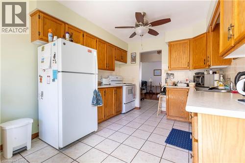 Kitchen featuring an abundance of wood-finish cabinetry, tile flooring, white appliances, and a ceiling fan with light fixture - 12 Spartan Drive, Brantford, ON - Indoor Photo Showing Kitchen