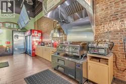 Commercial kitchen featuring a stainless steel range hood, griddle, and refrigerator - 