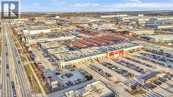 Aerial perspective of a commercial complex featuring multiple retail storefronts and extensive surface parking - 
