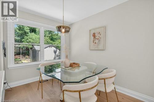 Dining area featuring wood-finish flooring, a contemporary pendant light fixture, and a large window offering exterior views - 603 Cornick Drive, Burlington, ON 