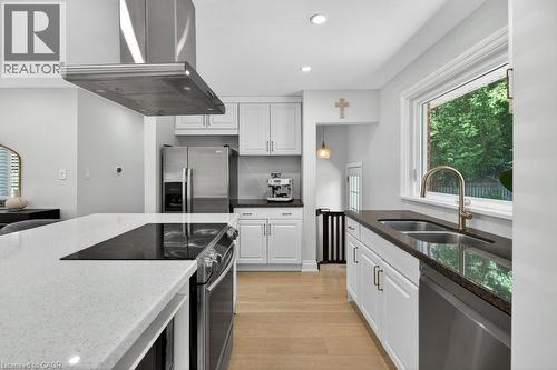 Kitchen featuring light wood-finish flooring, white cabinetry, stainless steel appliances, and a central island with a built-in cooktop and light-toned countertop - 603 Cornick Drive, Burlington, ON 