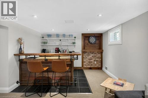 Custom-built wet bar featuring a wood-finish countertop, industrial-style pipe accents, and integrated shelving - 603 Cornick Drive, Burlington, ON 