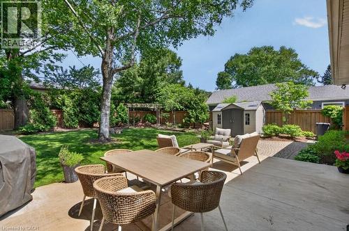 Expansive backyard featuring a large concrete patio, manicured lawn, and mature trees providing natural shade - 603 Cornick Drive, Burlington, ON 
