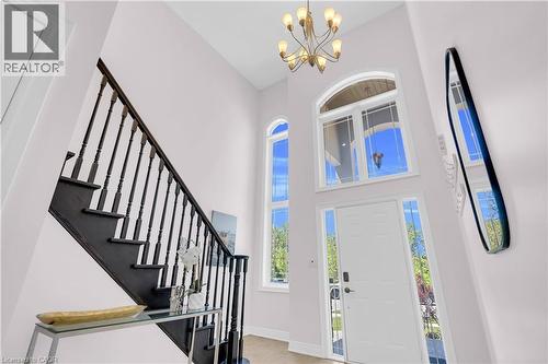 Two-story entryway featuring a dark wood-finish staircase with balusters, a white door with sidelights, and an arched transom window - 92 Desoto Drive, Hamilton, ON - Indoor Photo Showing Other Room