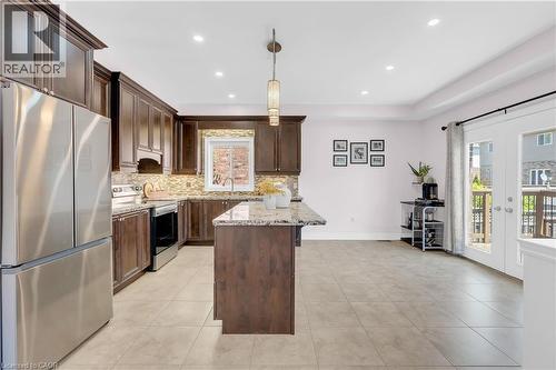 Spacious kitchen featuring dark wood cabinetry, stainless steel appliances, a large island with a stone countertop, a tile backsplash, and recessed lighting - 92 Desoto Drive, Hamilton, ON - Indoor Photo Showing Kitchen With Upgraded Kitchen